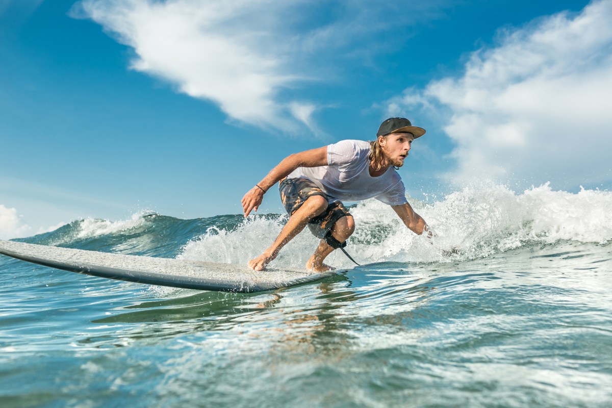 concentrated male surfer riding waves in ocean at Nusa Dua Beach, Bali, Indonesia a man riding a wave on a surfboard in the water