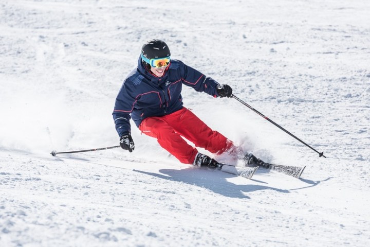 Person in ski gear skiing downhill on snow-covered slope.
