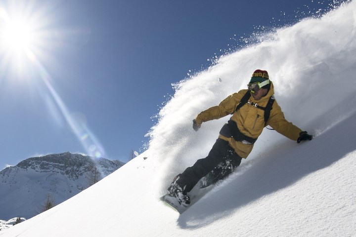 a man riding a snowboard down a snow covered slope