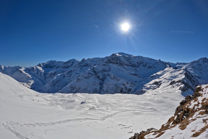 Snowy mountain landscape under bright sun and clear blue sky