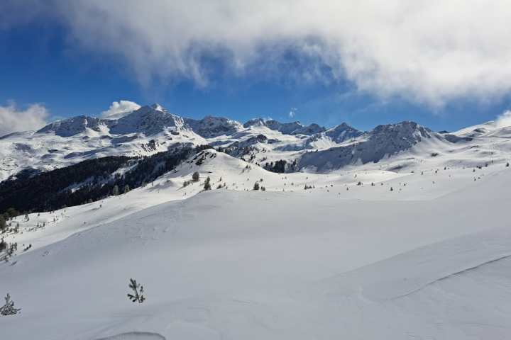 Snow-covered mountain landscape under a blue sky with scattered clouds.