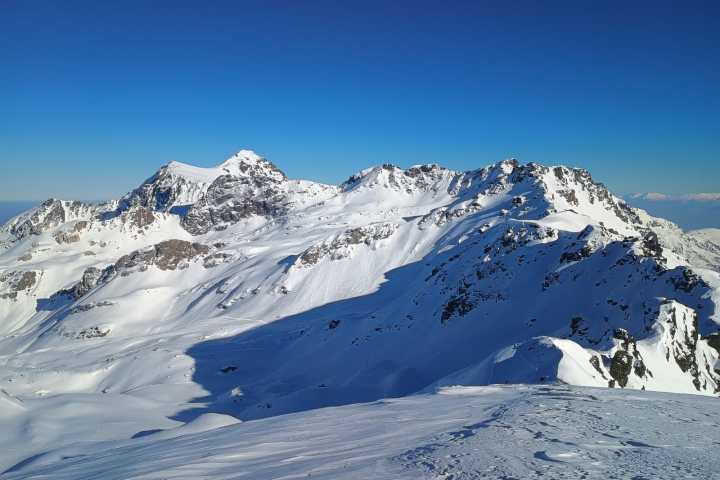 Snow-covered mountain range under a clear blue sky during daytime.