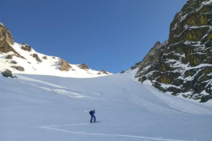 Person skiing on snowy mountain slope under clear blue sky.