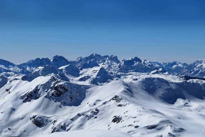 Snow-covered mountain range under a clear blue sky.