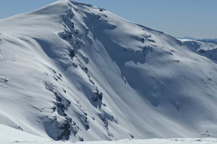 Snow-covered mountain peak under clear blue sky.