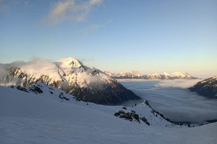 Snow-covered mountains and valley with clouds at sunrise.