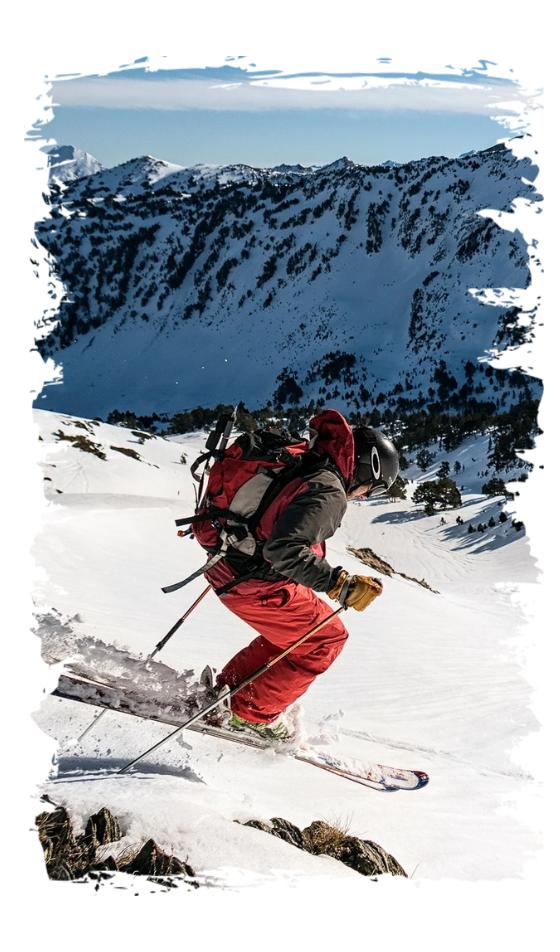 Person skiing downhill on snowy mountain with blue sky and distant peaks.