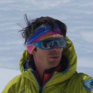 Person in colorful headband and jacket wearing sunglasses in a snowy environment.